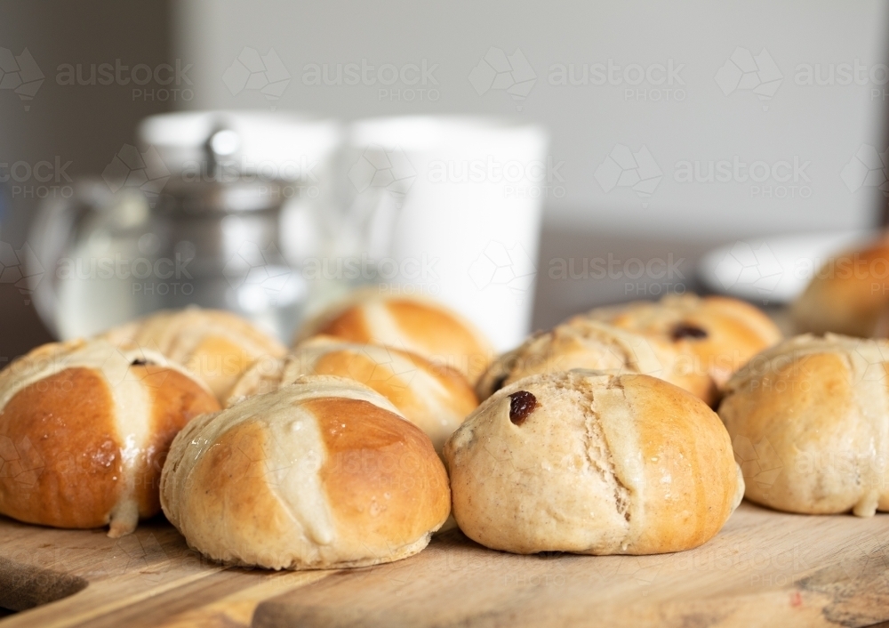 freshly made hot cross buns on table with teapot and cups - Australian Stock Image