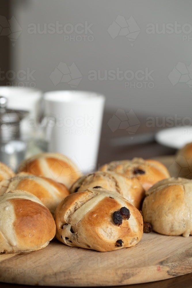freshly made hot cross buns on table with teapot and cups - Australian Stock Image