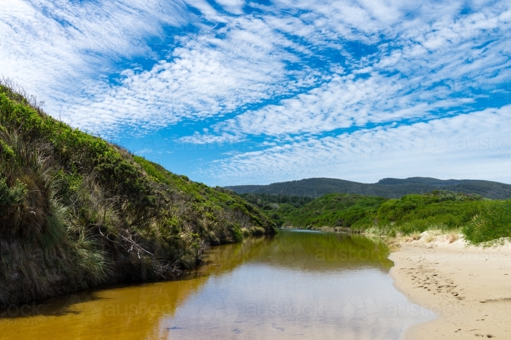 freshwater creek flowing into the ocean - Australian Stock Image