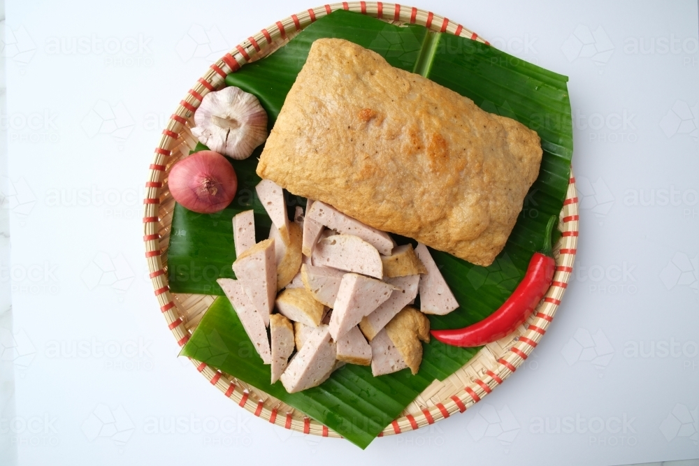 Image of Fried Cha Lua served on a banana leaf inside a woven basket ...