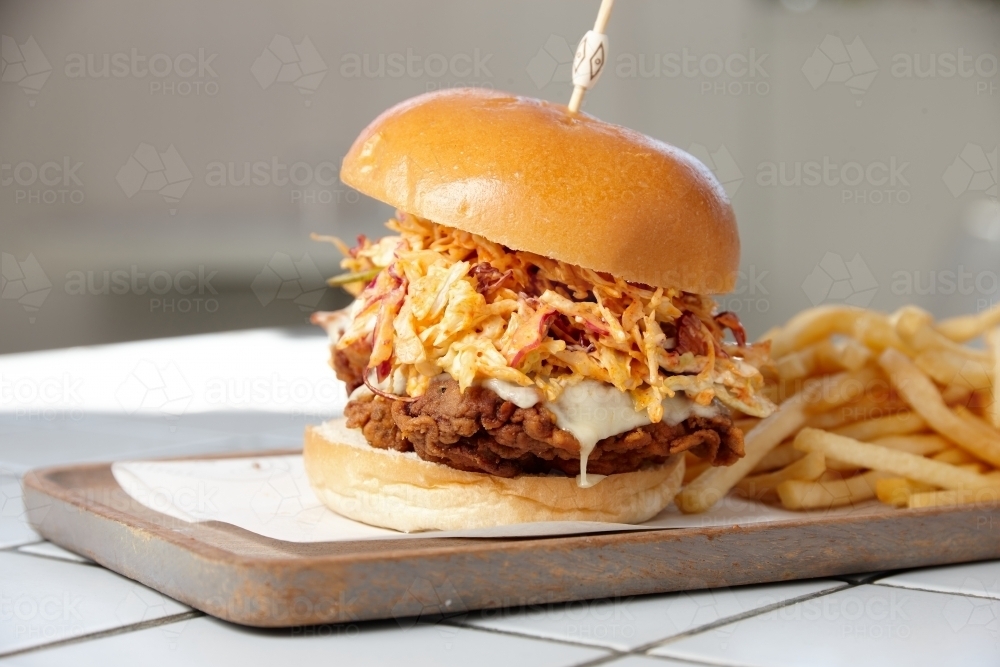 Fried chicken burger on board with french fries - Australian Stock Image