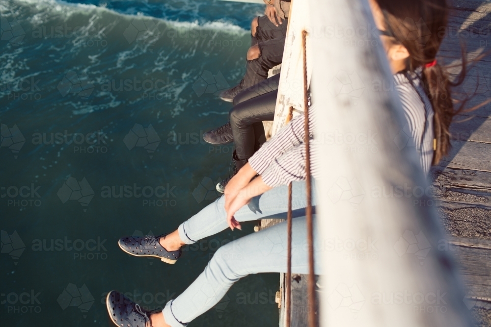 Friends dangling legs over a jetty - Australian Stock Image