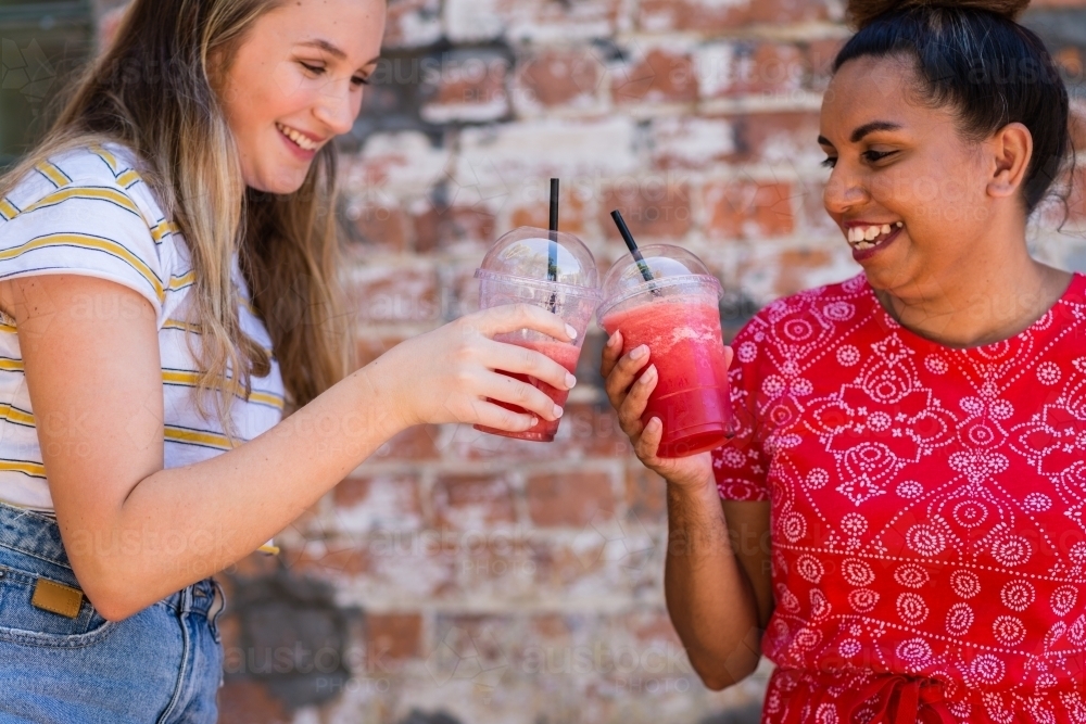 friends sharing smoothies - Australian Stock Image