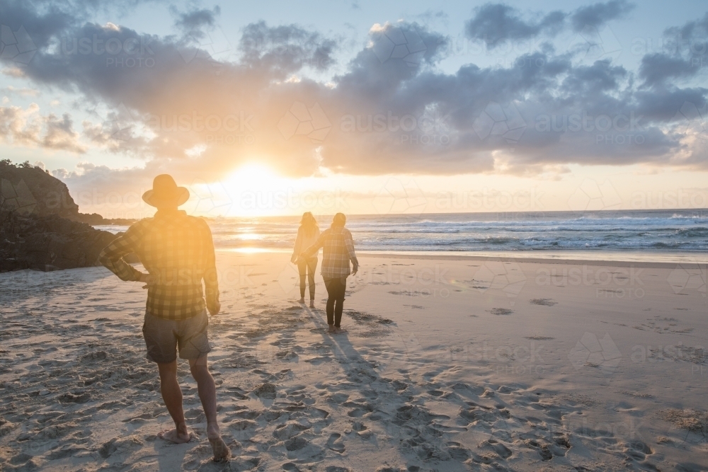 Friends walking on sandy beach in the morning sun - Australian Stock Image