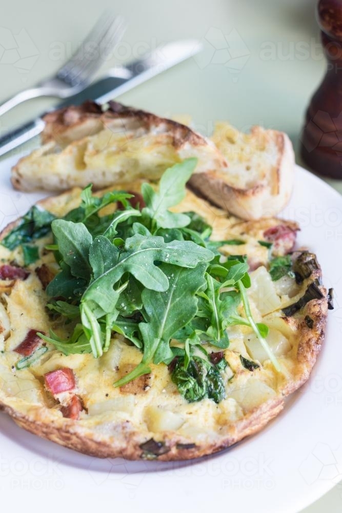 Frittata or omelette for breakfast, with fresh rocket leaves - Australian Stock Image