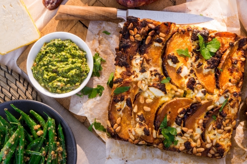 frittata with pumpkin, pine nuts, pesto and green beans in an outdoor setting - Australian Stock Image