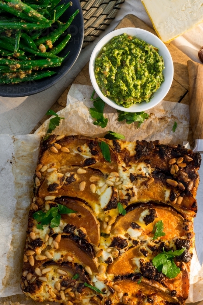 frittata with pumpkin, pine nuts, pesto and green beans in an outdoor setting - Australian Stock Image