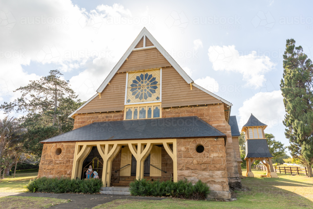 Front of historic stone chapel on green lawn with blue sky - Australian Stock Image