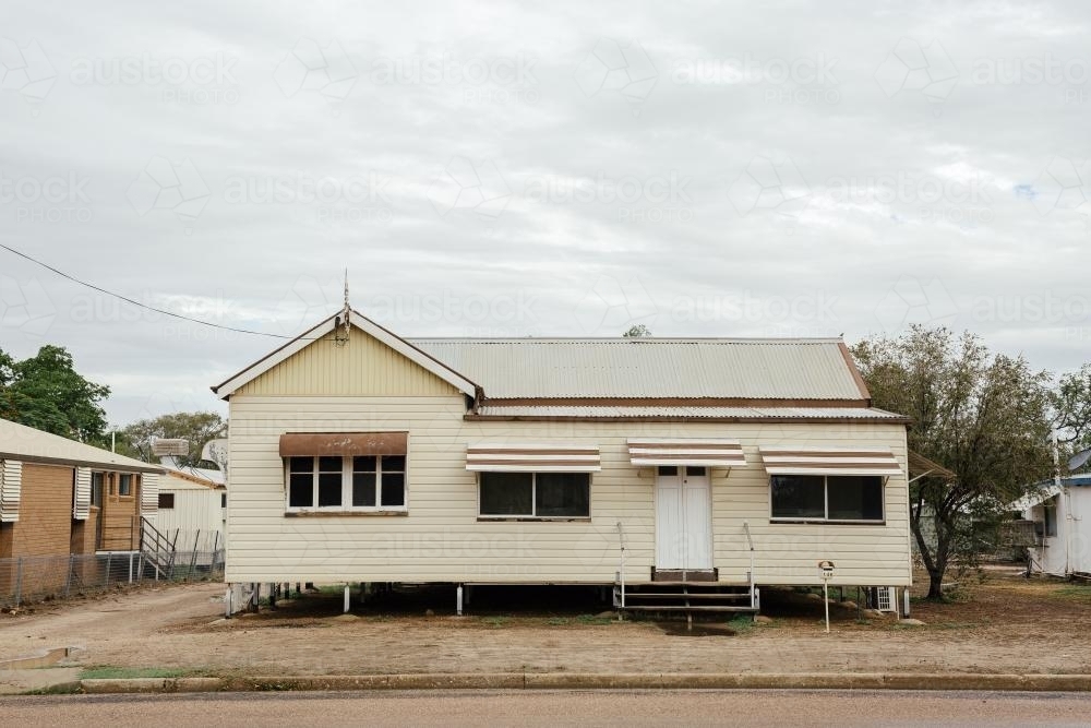 Front-on view of cream coloured Queenslander Home with brown trimming - Australian Stock Image