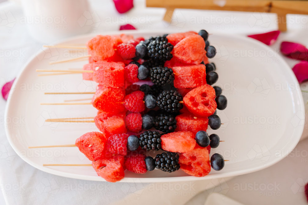 Fruit skewers sitting on a white plate - Australian Stock Image