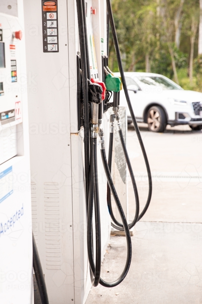fuel pumps at a petrol station with a car driving up in the background - Australian Stock Image