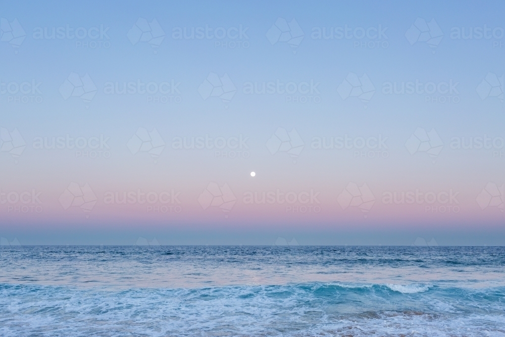 Full moon over blue sea water in pastel sky - Australian Stock Image