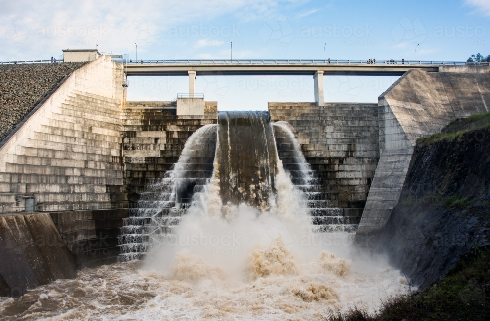 Full weir flowing with water while viewing platform above allows people to pass overhead. - Australian Stock Image