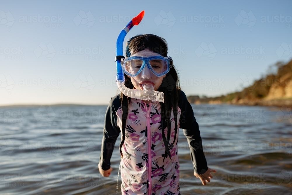 Fun portrait of a young girl standing in the ocean wearing a snorkel and mask - Australian Stock Image
