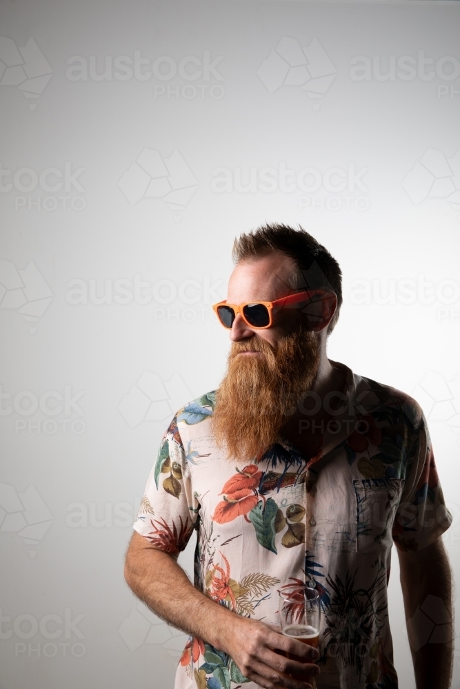 Funky man posing for photographs, holding a glass of beer - Australian Stock Image