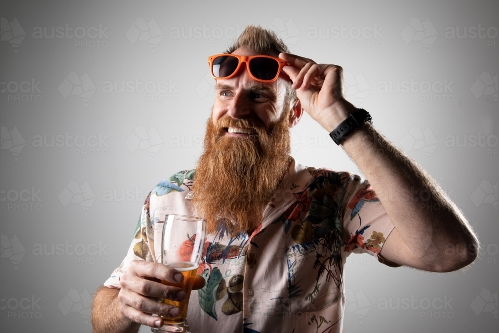 Funky man posing for photographs, holding a glass of beer - Australian Stock Image