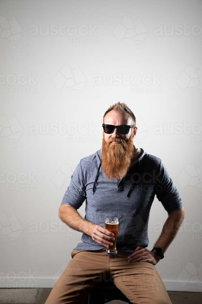 Funky man posing for photographs, holding a glass of beer - Australian Stock Image
