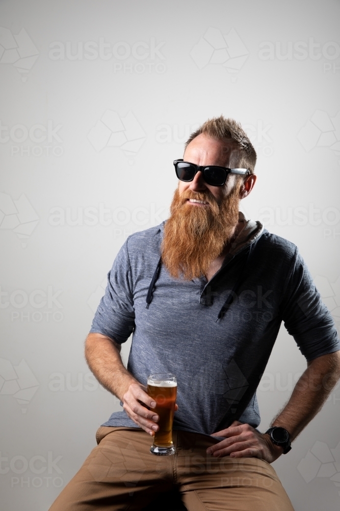 Funky man posing for photographs, holding a glass of beer - Australian Stock Image