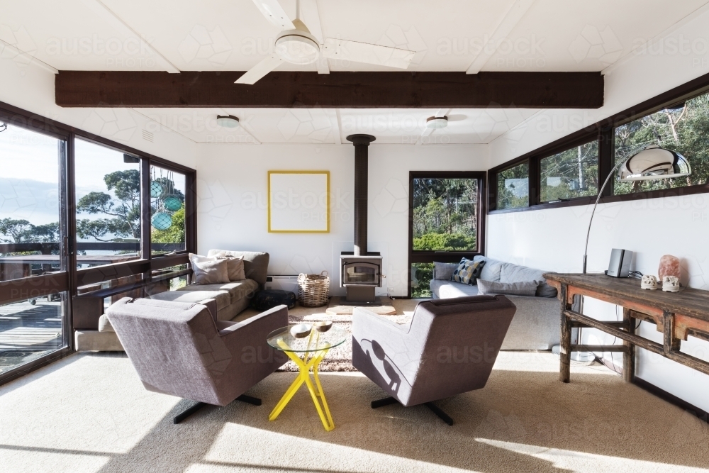 Funky retro beach house living room with 70s style recliner chairs and amazing views - Australian Stock Image