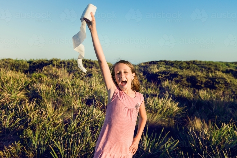 funny tween girl holding toilet paper in the air like an olympic torch - Australian Stock Image