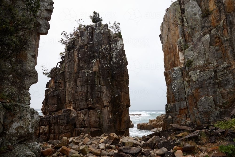 Image of Gap between coastal rocks on overcast morning - Austockphoto
