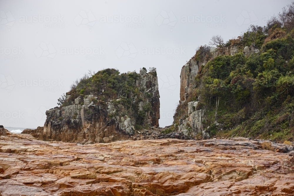 Gap in coastal rocky headland landscape on overcast morning - Australian Stock Image
