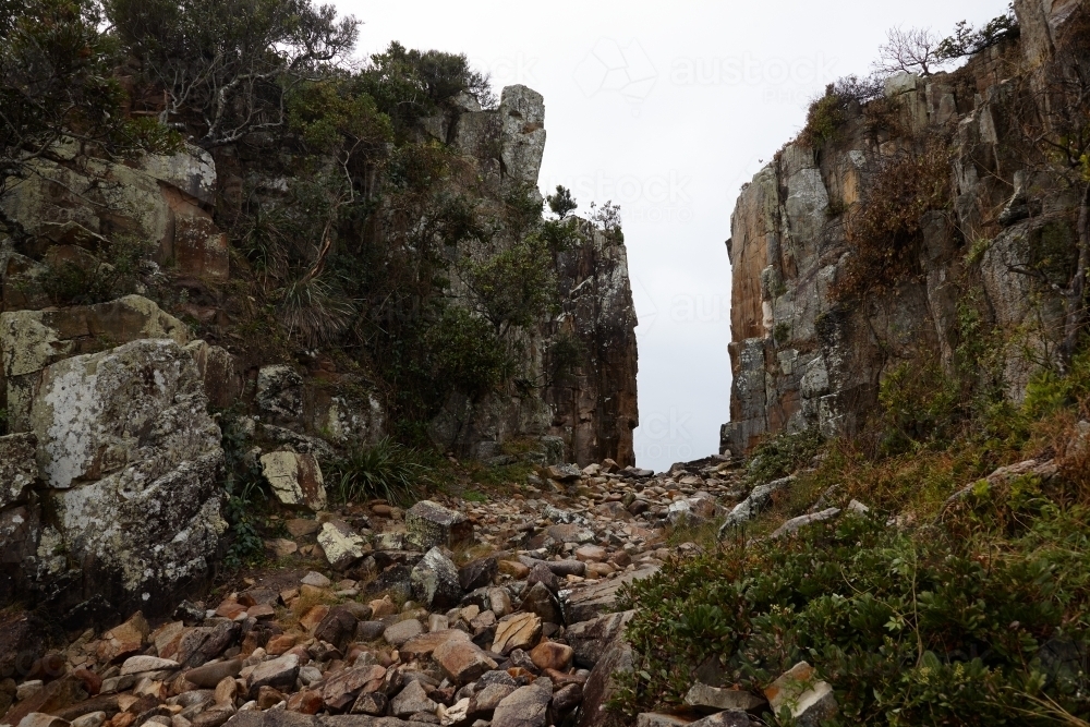 Gap in coastal rocky headland landscape on overcast morning - Australian Stock Image
