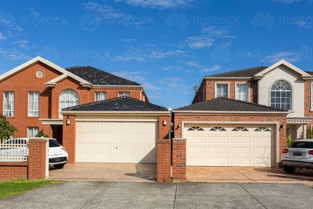 garages with roller doors and brick suburban homes in sunlit built close together - Australian Stock Image