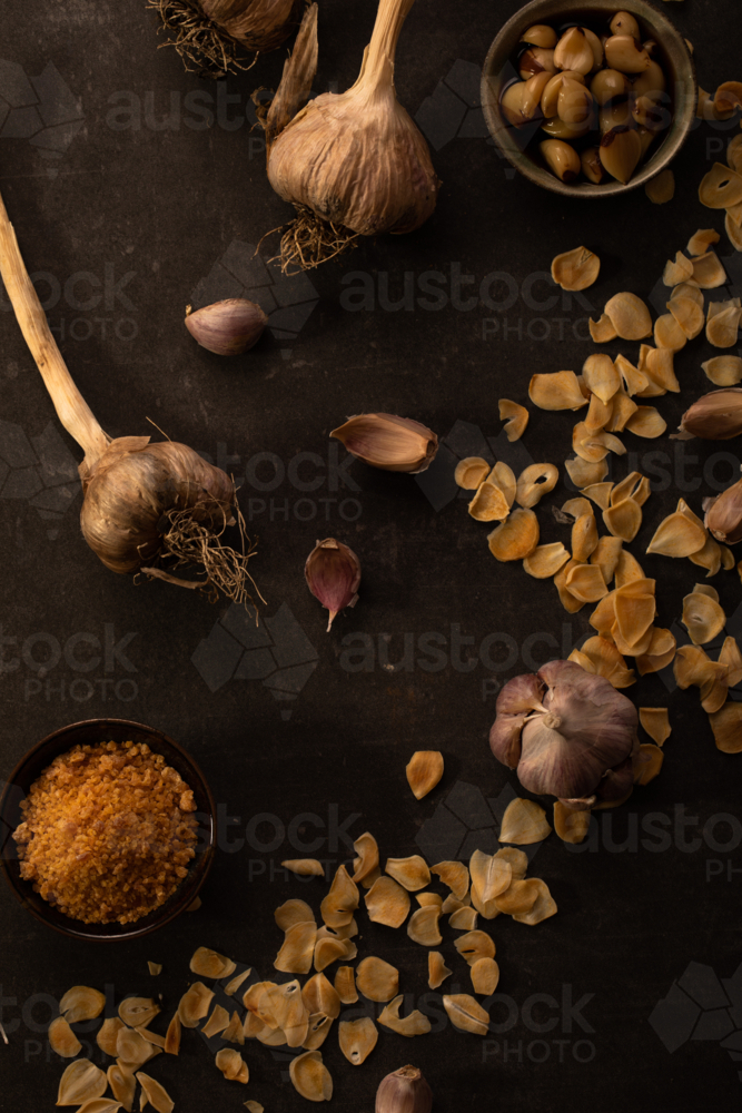 Garlic cloves and chips on dark surface - Australian Stock Image