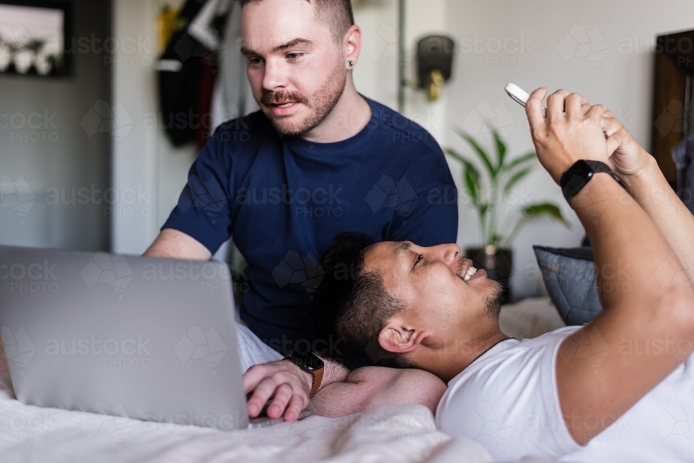 Gay couple hanging out at home in the bedroom - Australian Stock Image