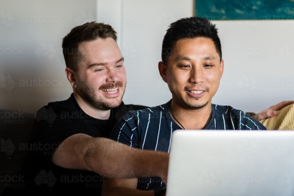 Gay couple on sofa with laptop - Australian Stock Image
