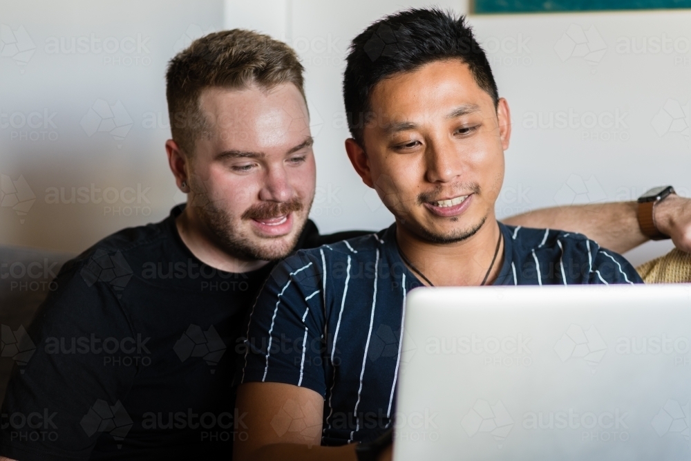 Gay couple on sofa with laptop - Australian Stock Image