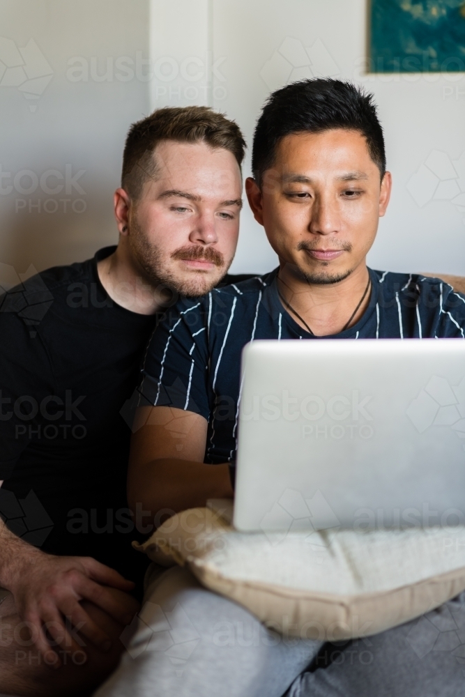 Gay couple on sofa with laptop - Australian Stock Image