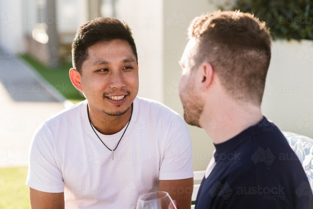 Gay couple outside smiling and talking together - Australian Stock Image