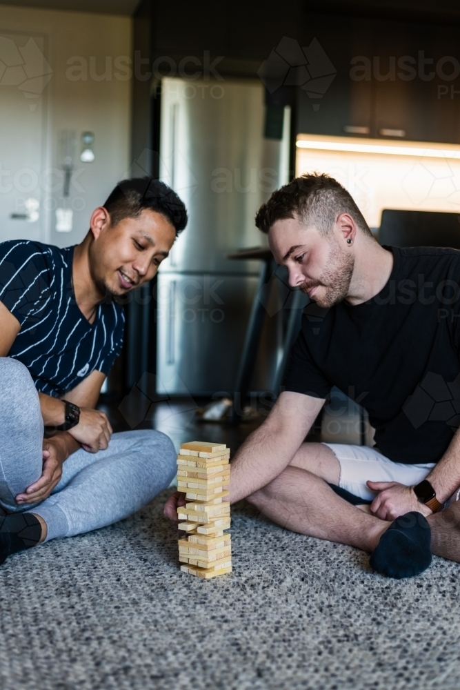 Gay couple playing fun block game at home - Australian Stock Image