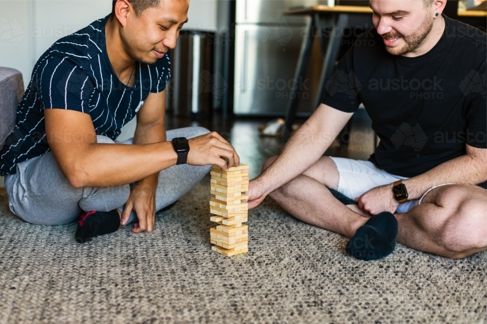 gay couple playing fun block game at home - Australian Stock Image