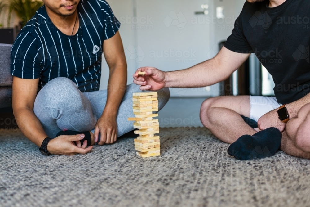 gay couple playing fun block game at home - Australian Stock Image
