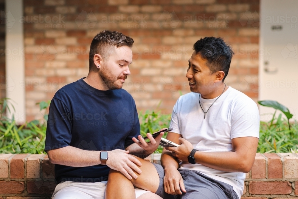Gay couple sitting on a bench - Australian Stock Image