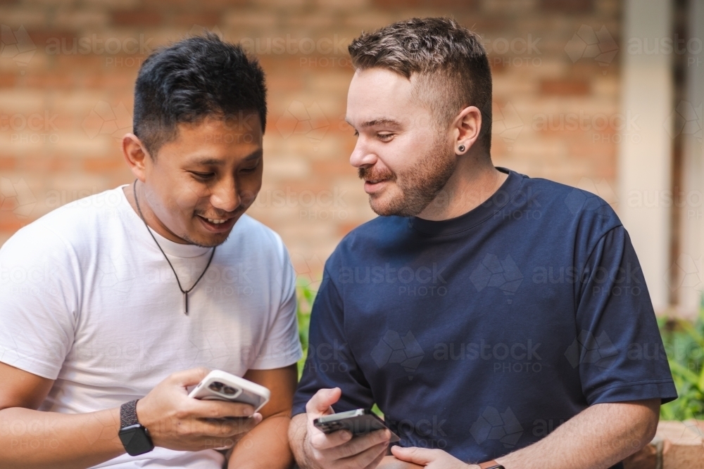 Gay couple sitting on a bench - Australian Stock Image