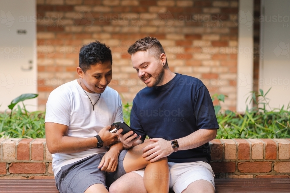 Gay couple sitting on a bench - Australian Stock Image
