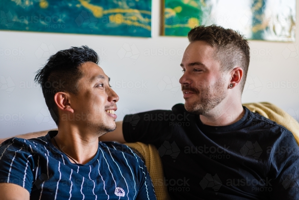 gay couple talking on couch - Australian Stock Image