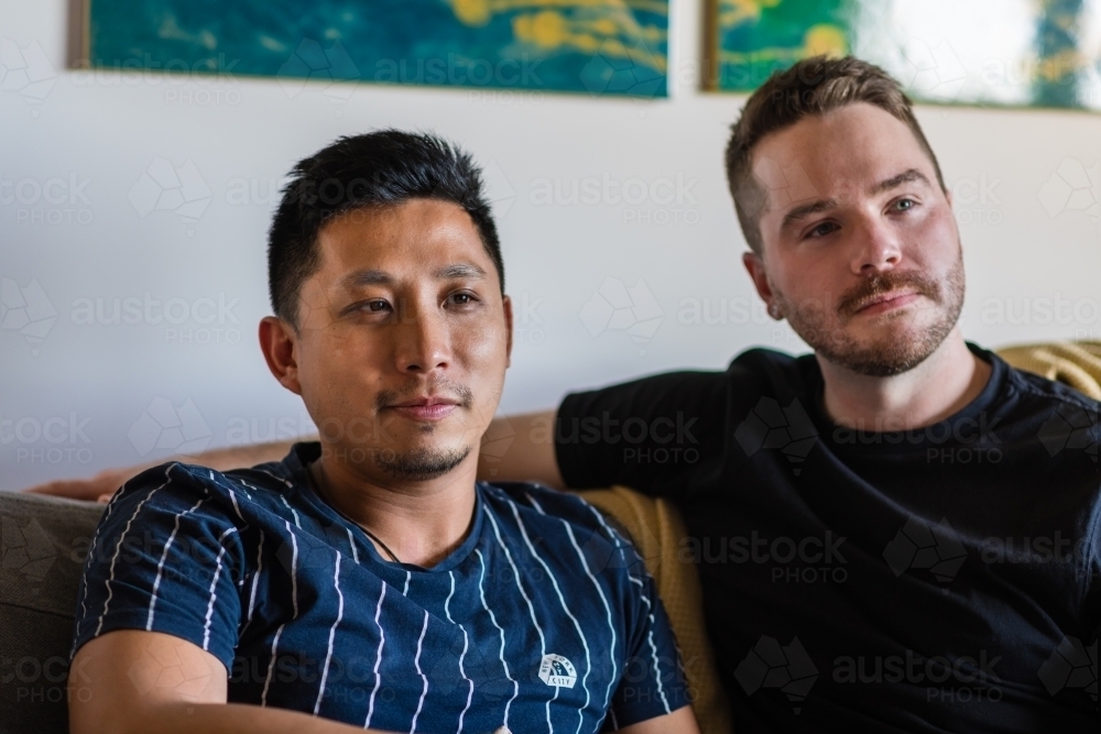 Gay male couple sitting on couch - Australian Stock Image