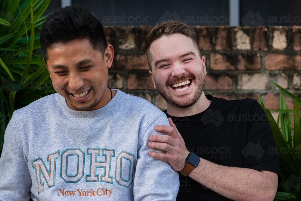gay men sitting outside, laughing - Australian Stock Image