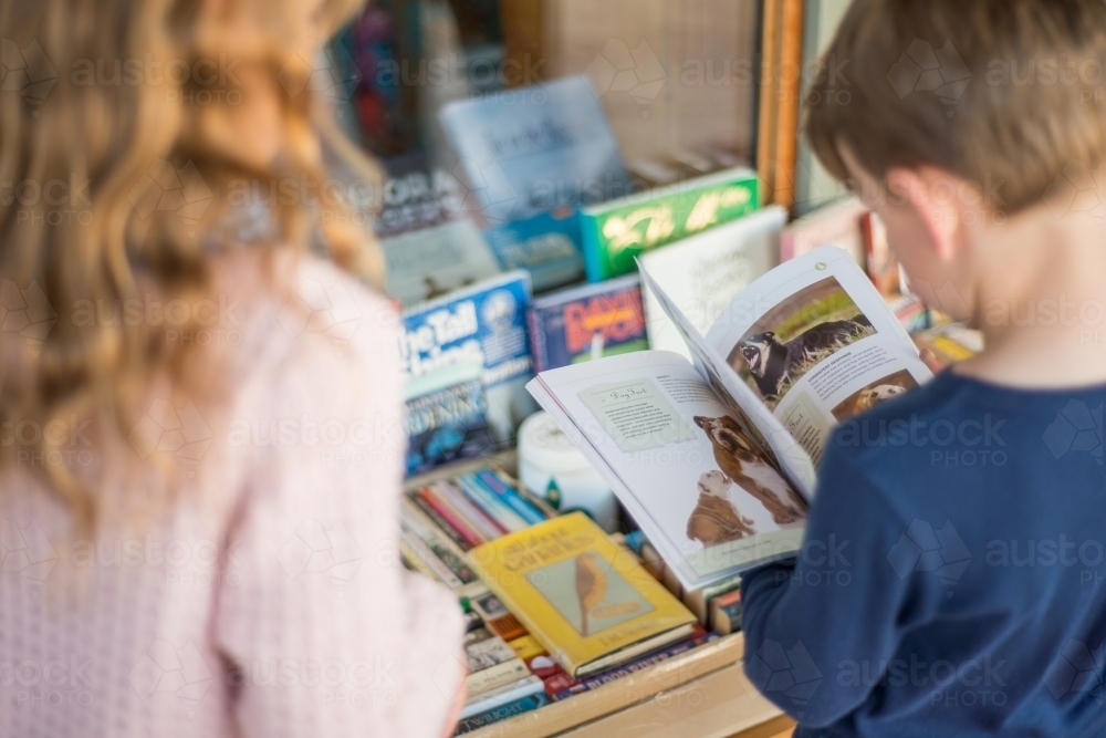 Girl and boy looking at books in front of a shop - Australian Stock Image