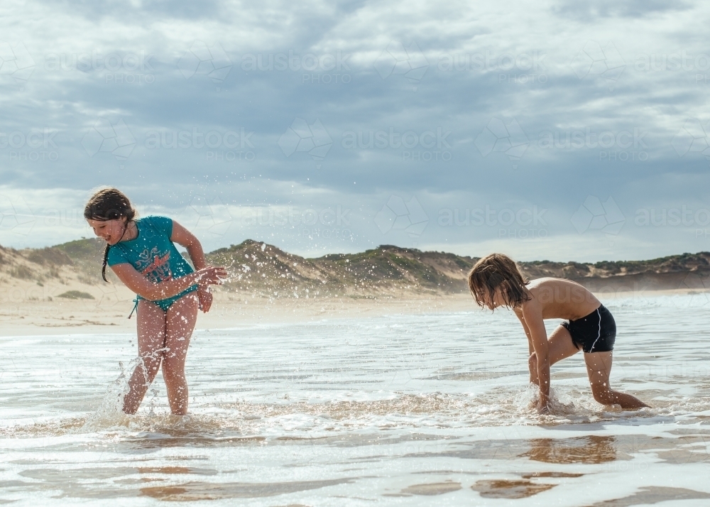 Girl and boy splashing in ocean - Australian Stock Image
