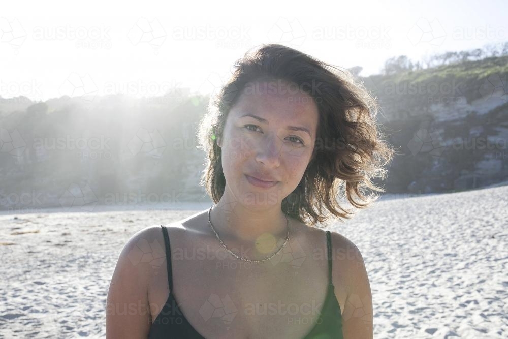 Girl at beach with sun behind her - Australian Stock Image