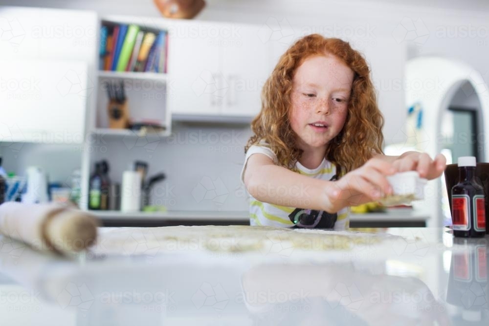Girl baking biscuits in the kitchen - Australian Stock Image