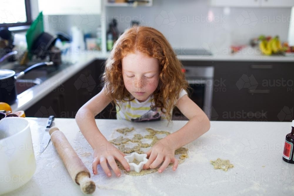 Girl baking biscuits in the kitchen - Australian Stock Image