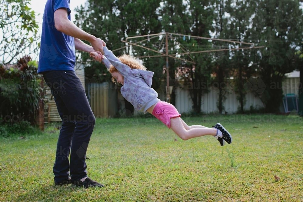 Girl being swung around in the backyard - Australian Stock Image