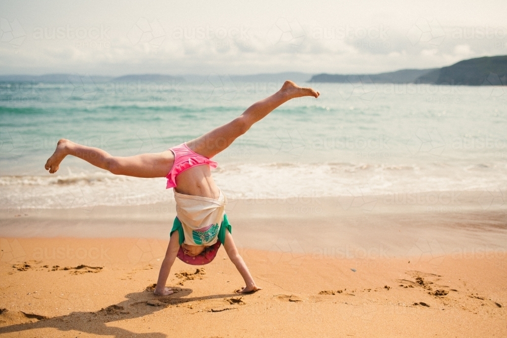 Girl cartwheeling on the beach - Australian Stock Image